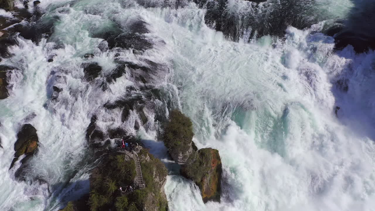 cámara lenta: tiro de seguimiento de una roca sentada en la cascada rugiente rheinfall en schaffhausen en suiza
