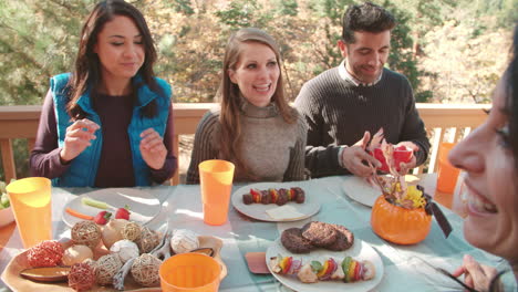 Over-shoulder-view-of-friends-eating-at-a-table-outdoors