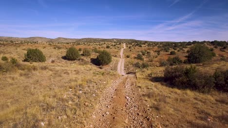 aerial, a closely following down a dirt road in the middle of the northern arizona, grasslands