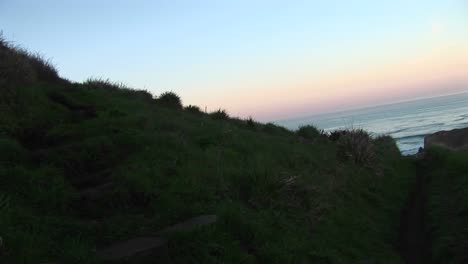 A-Low-Aerial-Shot-Follows-Coastal-Dunes-That-Stop-At-A-Lighthouse