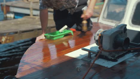 young man tipping varnish with brush wooden boat bow