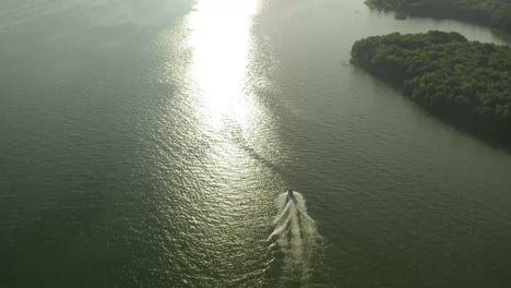 a motorboat all alone in the open waters heading towards a shoreline