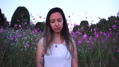 young latin woman sad and thinking deeply in the middle of a beautiful purple field with tinny flowers