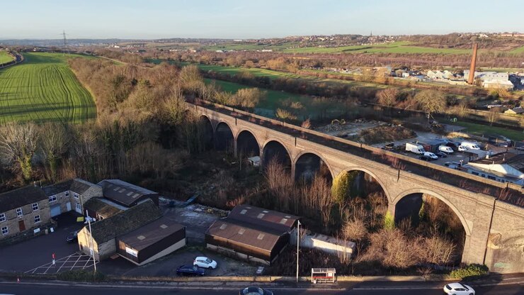 Aerial drone view of Seven Arches Viaduct in Shipley spanning road and buildings, historic stone railway structure across urban and industrial landscape West Yorkshire England