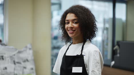 Portrait-of-and-african-american-worker-at-grocery-store-checkout,-friendly-smiling-to-camera