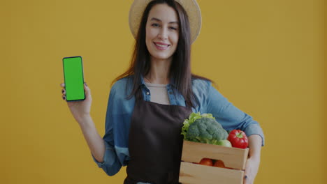 woman farmer holding produce and smartphone