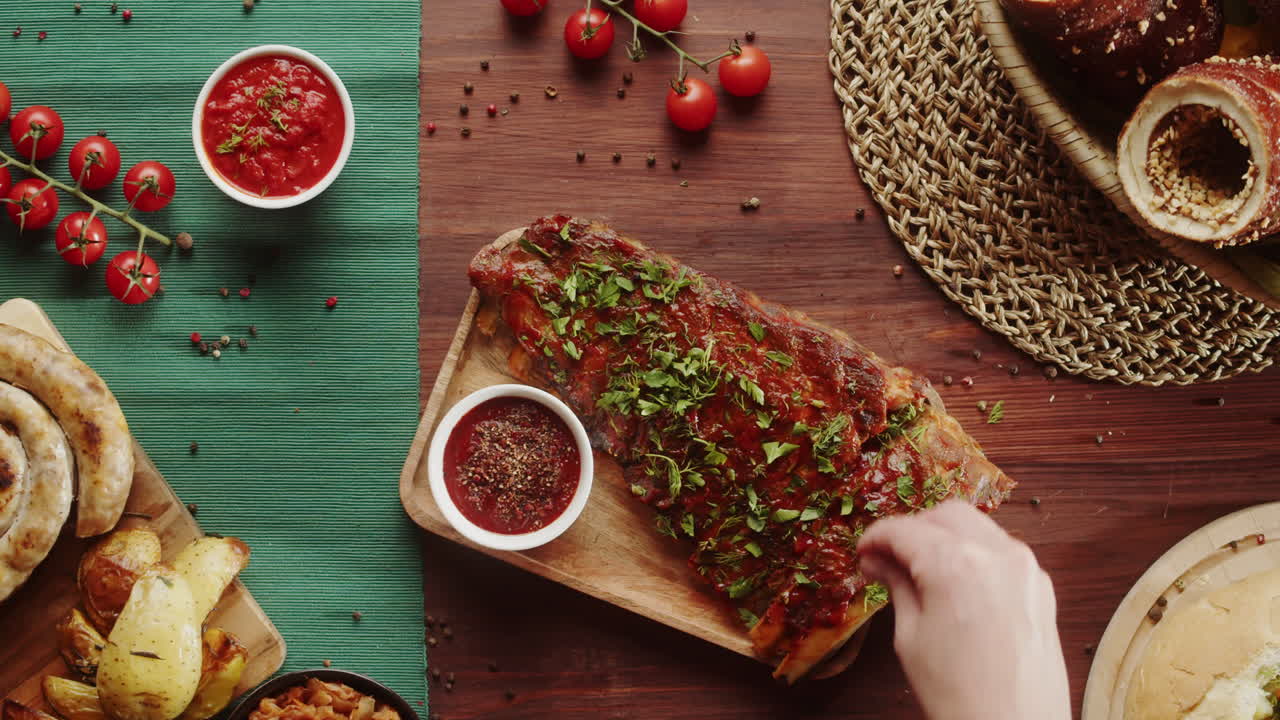Mano che guarnisce deliziose costine di maiale al barbecue con erbe fresche