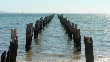 Remains-Of-Ruined-Jetty-Or-Pier-Stretching-Out-Into-Bay,-SLOW-MOTION