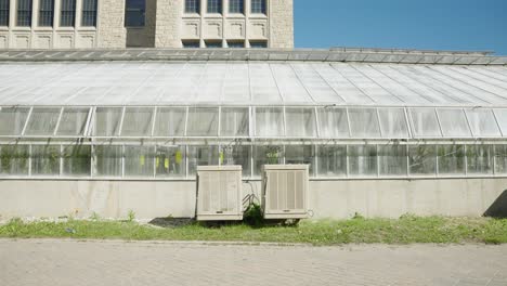 two large air conditioning units outside greenhouse with hazy windows and sidewalk