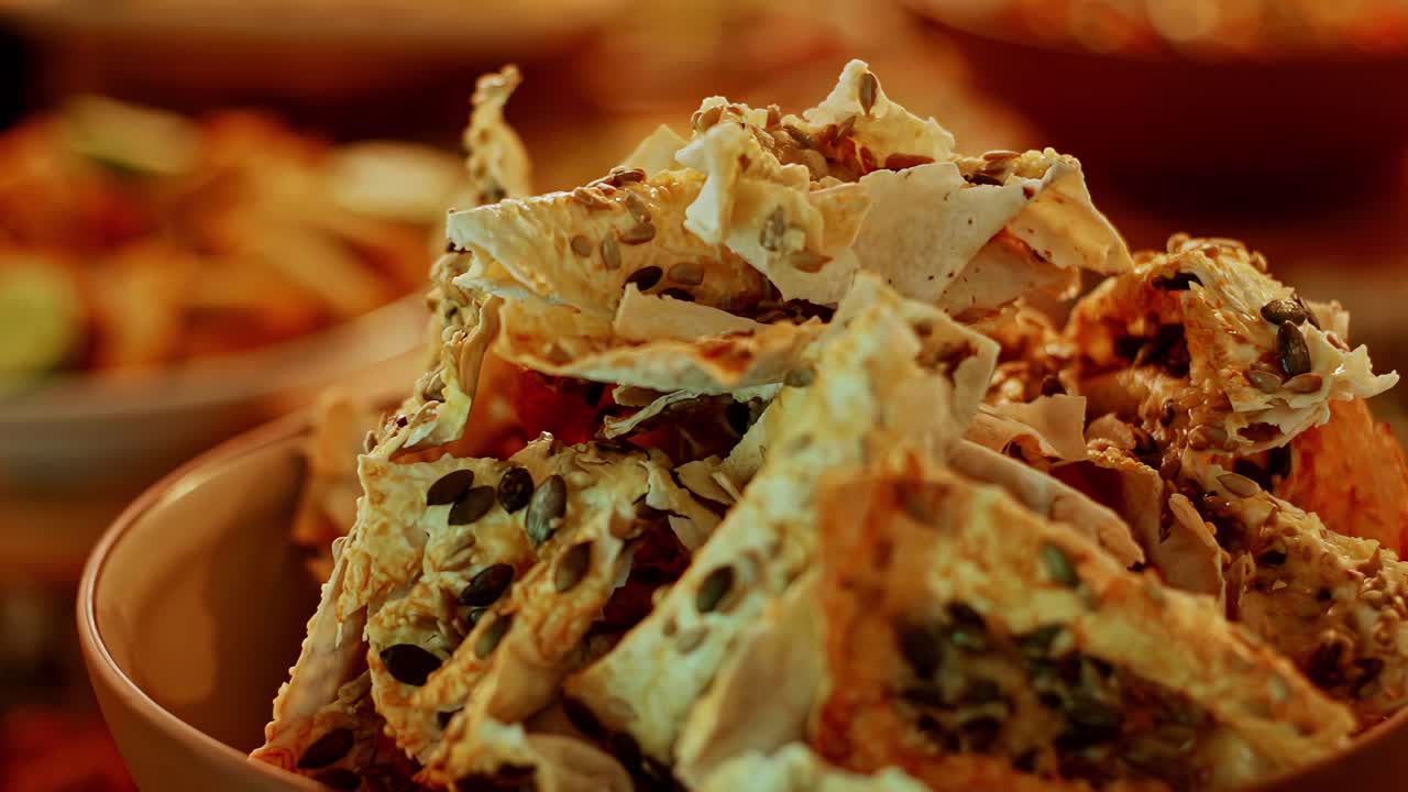 A rack focus shot moves from a wide view of a lavish buffet table laden with traditional Latvian dishes to a delicious close-up of crispy, seed-covered crackers