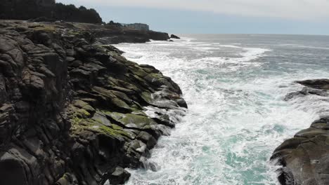 drone flies between two rocks in the water on the coast