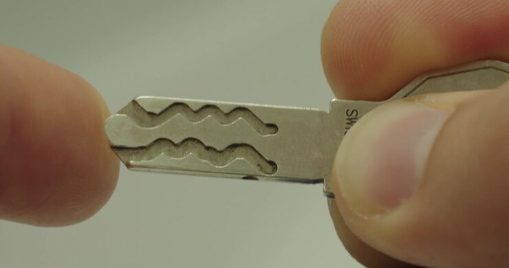Extreme macro view of a metal security key held between fingers. Concept of access control, home security, locking systems, property protection, and everyday household objects.