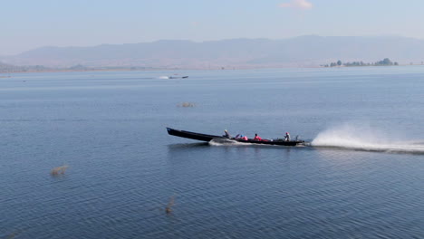 aerial drone shot of traditional long-tail boat tour on inle lake during sunny day in myanmar