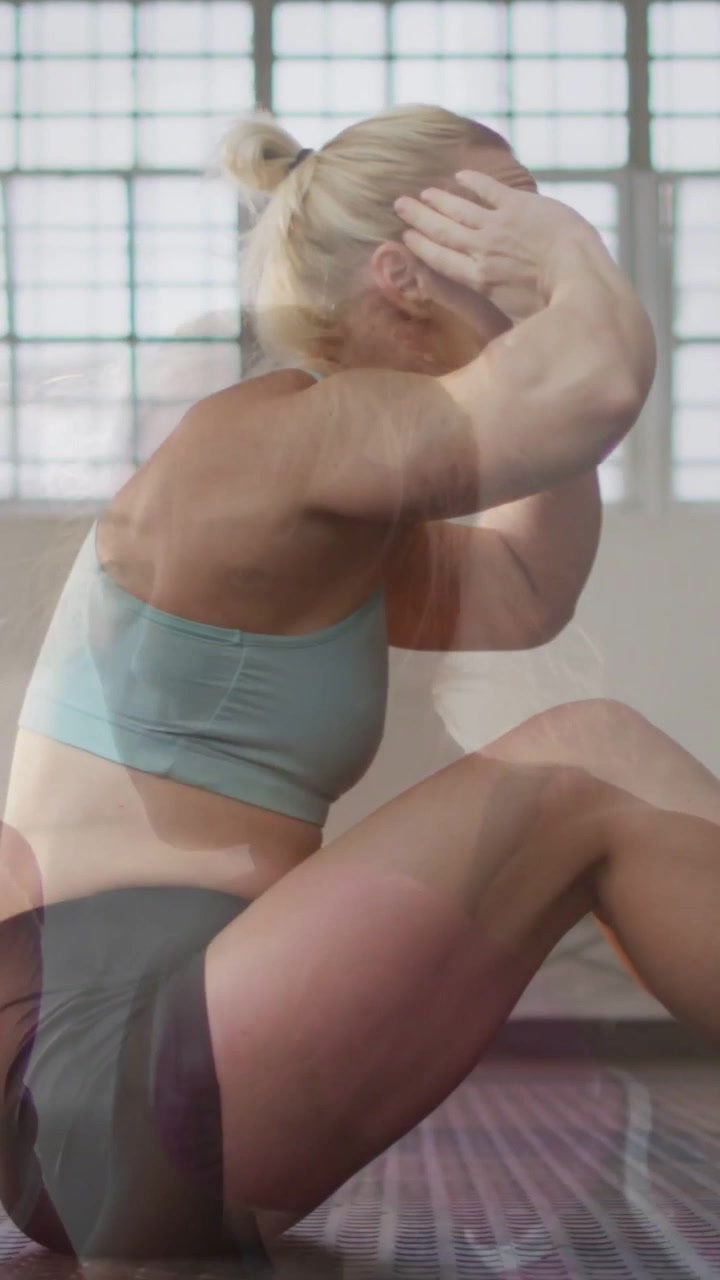 Video verticale: Donna che inizia un crunch sollevando il busto su un tappetino, con sovrapposizioni "fantasma" che mostrano i progressi di fitness