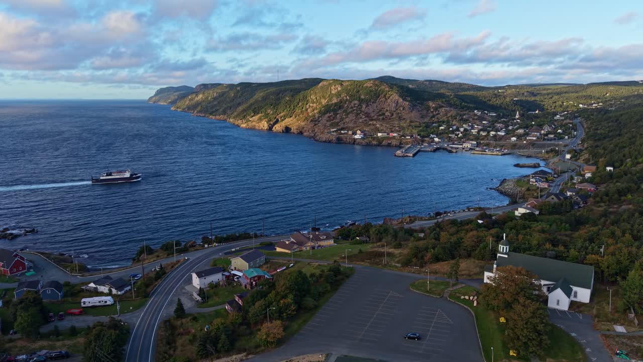 Drone footage captures a panoramic view of Portugal Cove’s harbor and surrounding hills in Newfoundland, highlighting the rugged coastline, village buildings and lush landscape