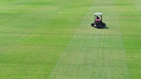 4k-Footage:-A-staff-on-a-lawn-mowing-vehicle-prepare-a-sports-field-on-a-sunny-summer-day-in-Dubai,-United-Arab-Emirates