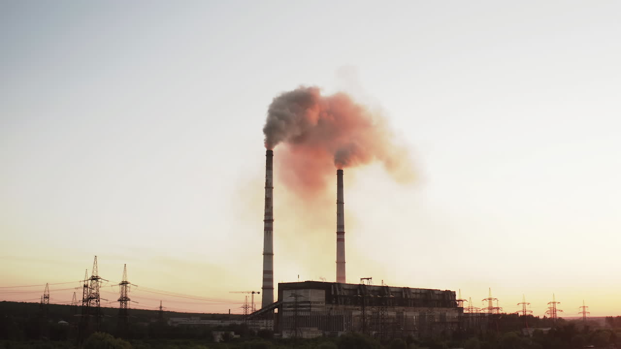 En Static view of the high-voltage tower sky background, factory pipe with smoke over it. Earth pollution and industrialization concept. Selective focus