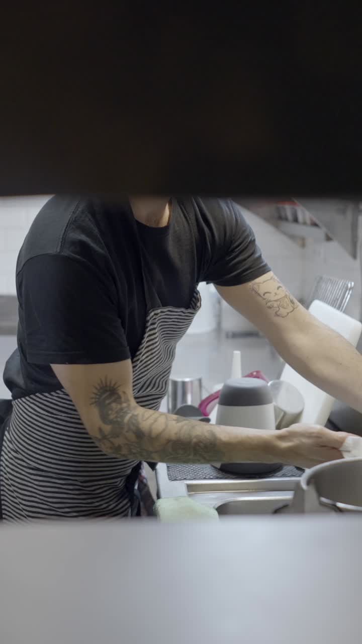 A chef working in a commercial kitchen, performing food preparation and cleaning duties