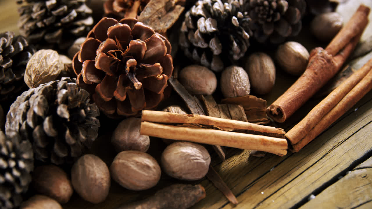 Pine cones and cinnamon sticks on wooden table 4k