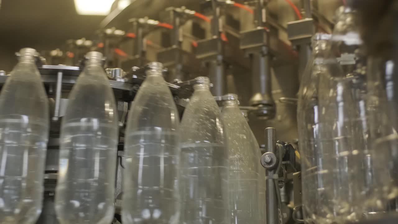 la máquina de llenado automático vierte agua en botellas de plástico para mascotas en una moderna planta de bebidas