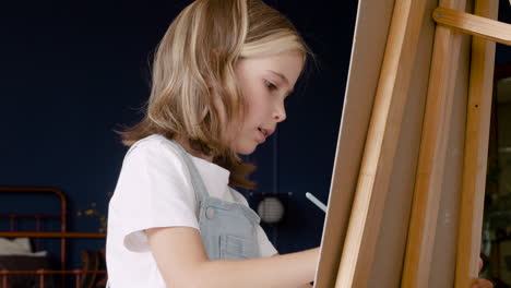 close up view of a girl's face concentrating and painting on a lectern in living room 1