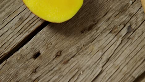 halved mango and knife on wooden table