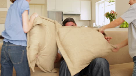 Cute-children-hitting-their-father-with-cushions