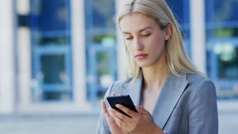 joven empresaria usando un teléfono inteligente cerca del edificio
