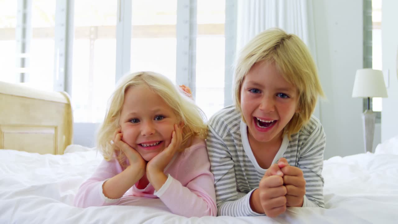 Happy siblings relaxing on bed in bedroom 4k