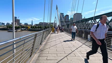 people walking on hungerford bridge in london