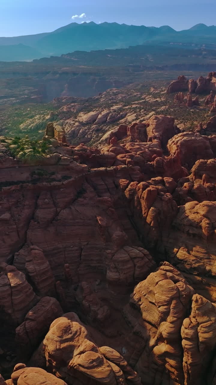 Sunlit canyon mountains in Arches National park in Utah, United States. Rising over the amazing rocks on the uneven landscape. Vertical video