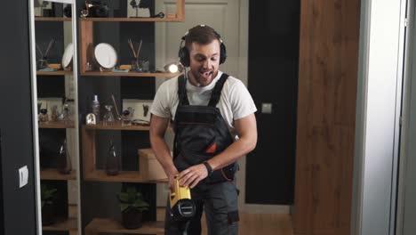 Primer-Plano-De-Hombre-En-Uniforme-Cantando-En-Auriculares-Y-Limpiando-Con-Aspiradora-Inalámbrica