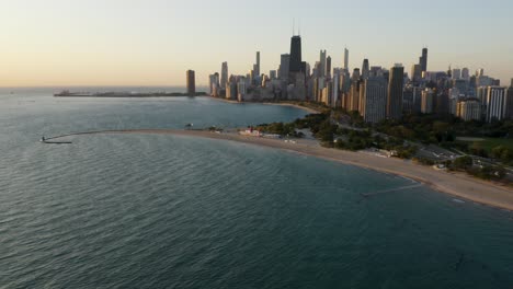 Alta-Vista-Aérea-De-Las-Playas-Del-Lago-Michigan-Con-El-Horizonte-De-Chicago-En-El-Fondo-Durante-La-Hora-Dorada