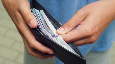 a man looks at a wallet full of banknotes 02