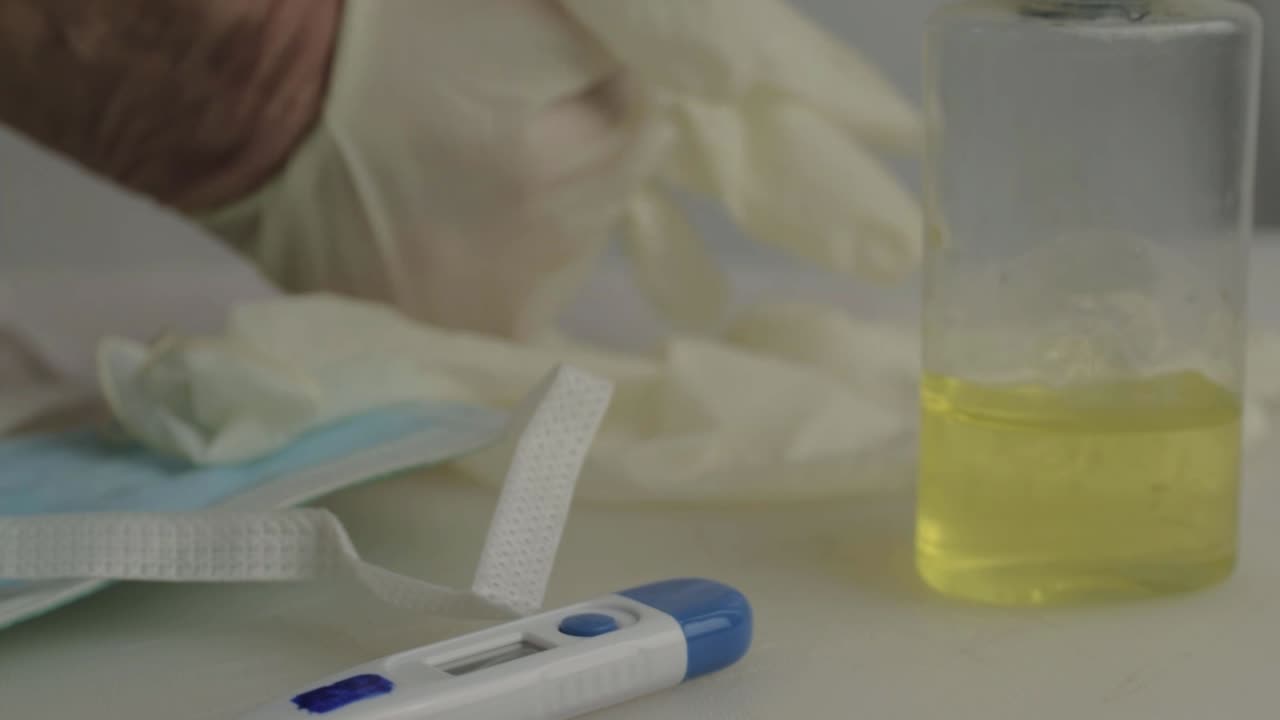 Mano che indossa guanti igienici con sfondo di forniture mediche, primo piano