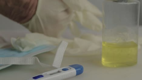 mano poniéndose guantes higiénicos con suministros médicos primer plano de fondo