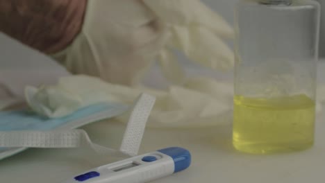 hand putting on hygienic gloves with medical supplies background close up shot