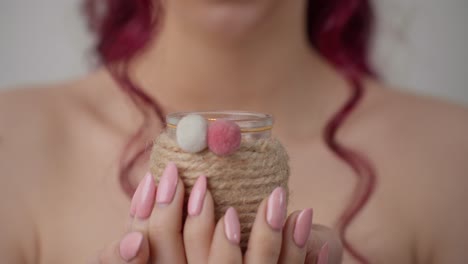 close up of woman holding small ornate glass jar