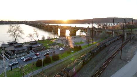 downtown riverfront in columbia, pennsylvania at sunset, with an amtrak depot, spectacular bridge crossing the river and freight trains passing by