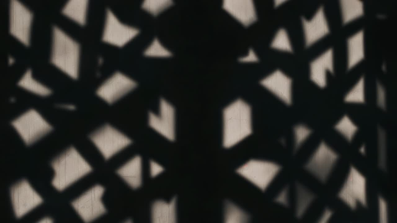 Showing patterned lattice shadow shifting against wall while light source shifting raising contrast