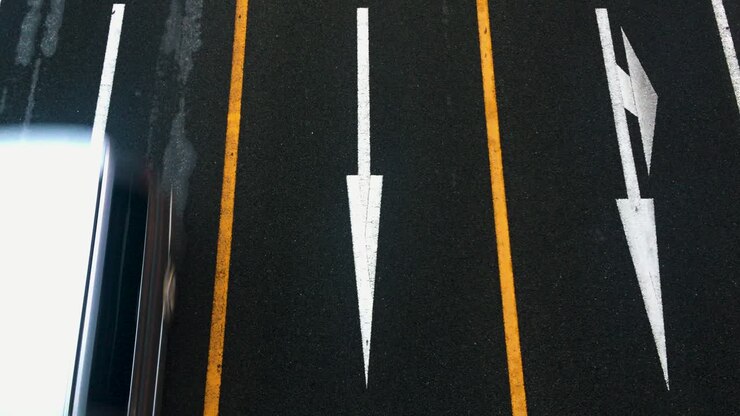 Overhead shot of lanes and arrows pointing down with trucks, buses and traffic driving by