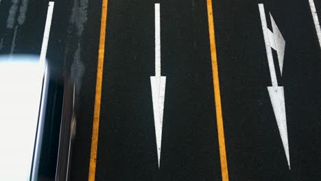 Overhead-shot-of-lanes-and-arrows-pointing-down-with-trucks,-buses-and-traffic-driving-by