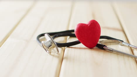 video de estetoscopio con corazón rojo en fondo de madera con espacio de copia