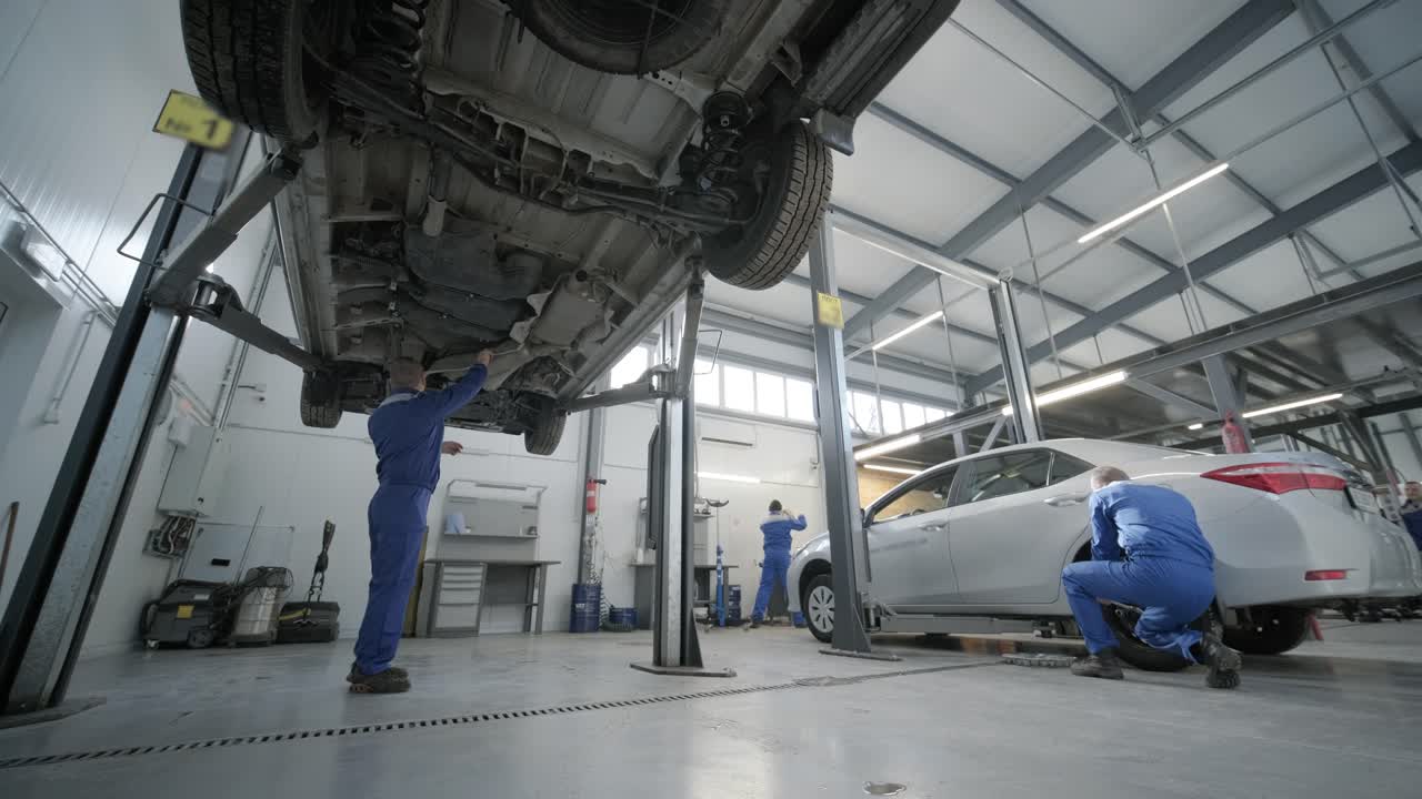 mecánico de automóviles que trabaja debajo de la máquina de elevación de automóviles en el garaje. tienda de reparación de autos. servicio de automóviles, reparación.