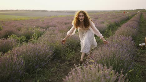 mujer con un vestido rosa corriendo alegremente a través de un campo de lavanda y sonriendo