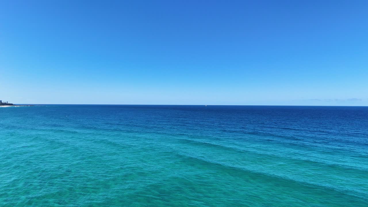 바다의 파도와 은 파란 하늘 아래의 해안선