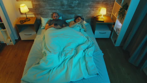 top view of couple in the bedroom late at night using their phones