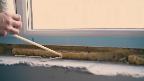 builder applies spray foam insulation on windowsill closeup