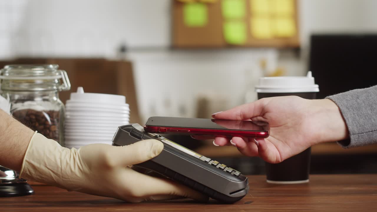 Paying with smartphone close-up, using NFC technology in a restaurant. Customer pays by mobile phone, contactless technology, touch-free payment in a cafe.