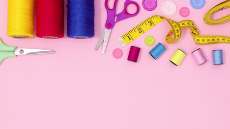 creative sewing and knitting craft items appear on top of pastel pink background. stop motion flat lay